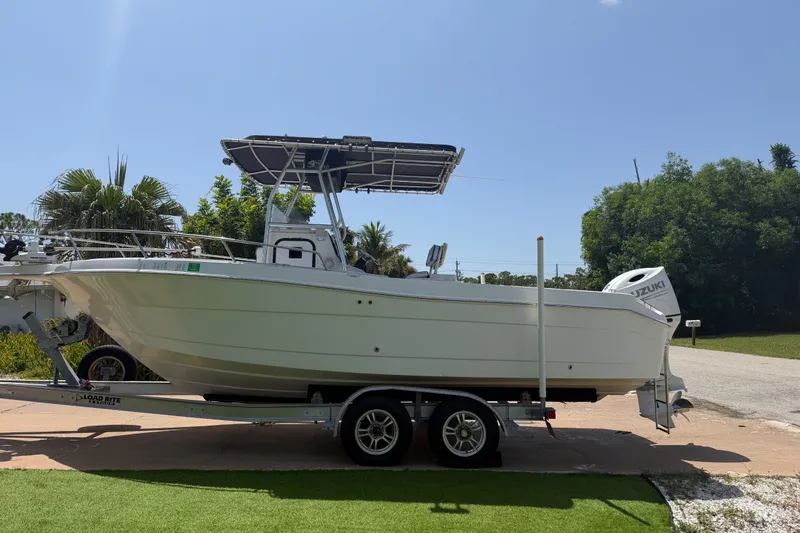 The Image of 2003 Robalo R230 Center Console boat on trailer, parked outdoors under clear sky. - 0