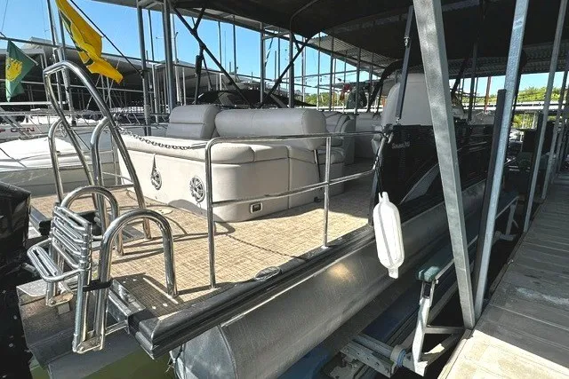 Slide: The Image of 2019 Harris Sunliner 240 pontoon boat docked, featuring spacious seating and sleek design. - 5