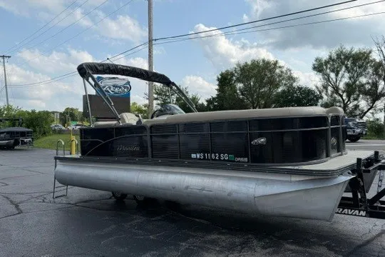 Slide: The Image of 2017 Manitou 22 Oasis Standard pontoon boat parked on pavement under a cloudy sky. - 6