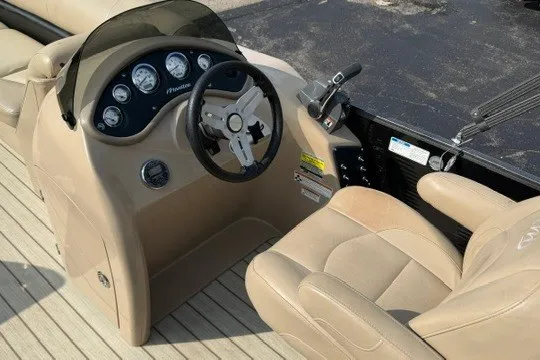 Slide: The Image of 2017 Manitou 22 Oasis Standard boat dashboard with steering wheel and beige seating. - 13
