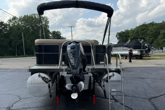 Slide: The Image of 2017 Manitou 22 Oasis Standard pontoon boat with outboard motor and canopy, parked on pavement. - 4