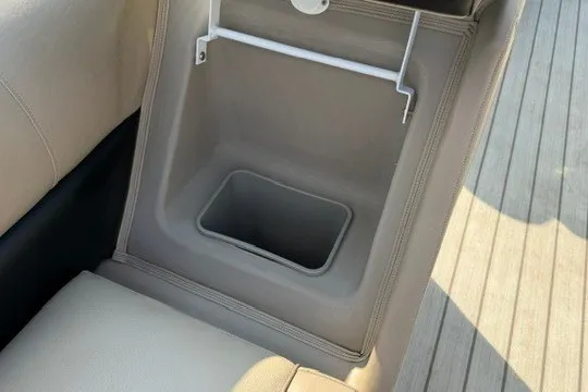 Slide: The Image of 2017 Manitou 22 Oasis Standard boat seat storage compartment, beige interior, open lid. - 31