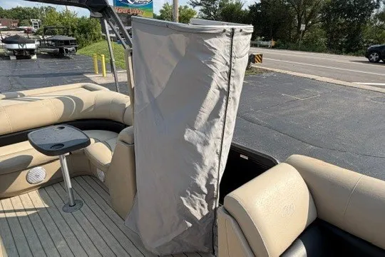 Slide: The Image of 2017 Manitou 22 Oasis Standard boat interior with beige seating and privacy curtain. - 28
