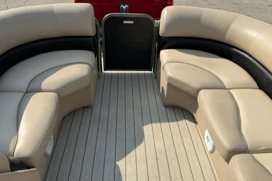 Slide: The Image of 2017 Manitou 22 Oasis Standard pontoon boat interior with beige seating and wood flooring. - 22