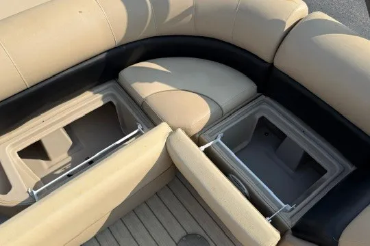 Slide: The Image of 2017 Manitou 22 Oasis Standard boat with open storage compartments and beige seating. - 32