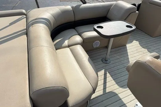 Slide: The Image of 2017 Manitou 22 Oasis Standard boat interior with beige seating and a small table. - 11
