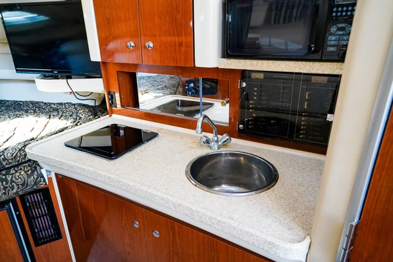 Slide: The Image of 2004 Regal Commodore 2860 boat interior with kitchenette, featuring sink, stove, and microwave. - 18
