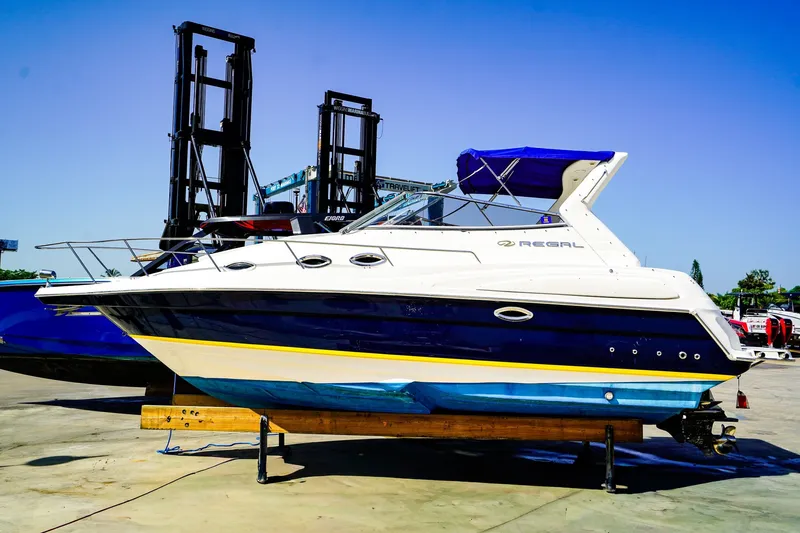 Slide: The Image of 2004 Regal Commodore 2860 boat on dry dock, blue and white hull, sunny day. - 1