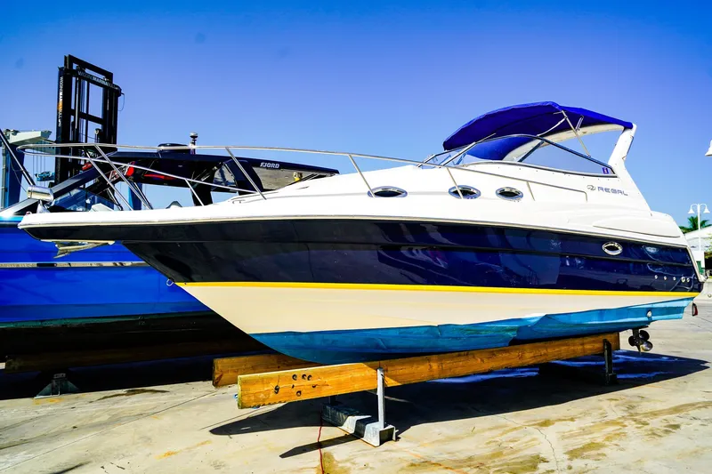 The Image of 2004 Regal Commodore 2860 boat on dry dock, blue and white exterior, sunny day. - 0