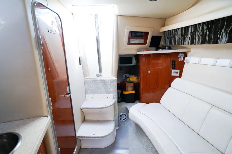 Slide: The Image of Interior of 2004 Regal Commodore 2860 boat, featuring white seating and wooden cabinetry. - 23