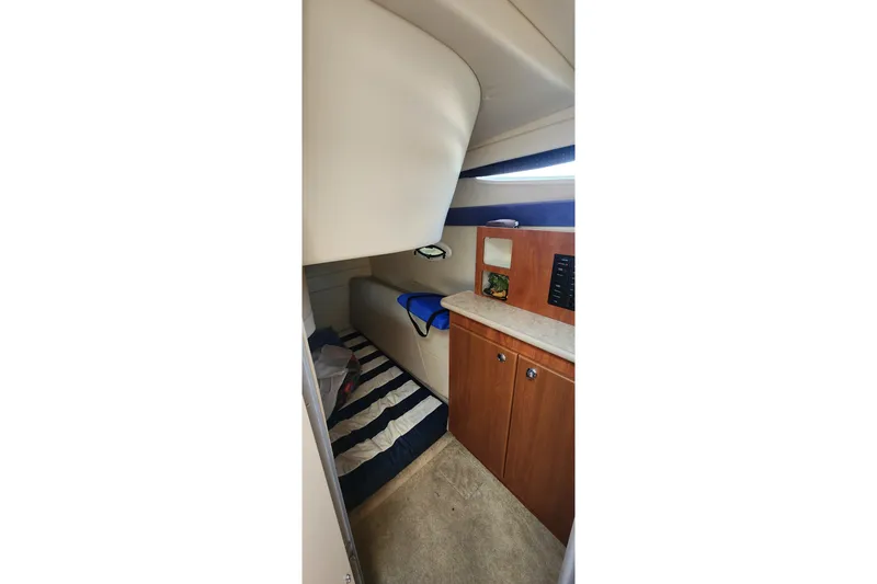 Slide: The Image of Interior cabin of 2008 Bayliner 300 boat with striped bedding and wooden cabinetry. - 11