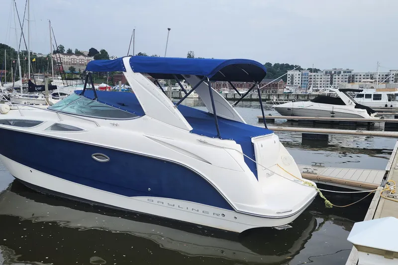 Slide: The Image of 2008 Bayliner 300 boat docked at a marina, featuring a blue and white design. - 2
