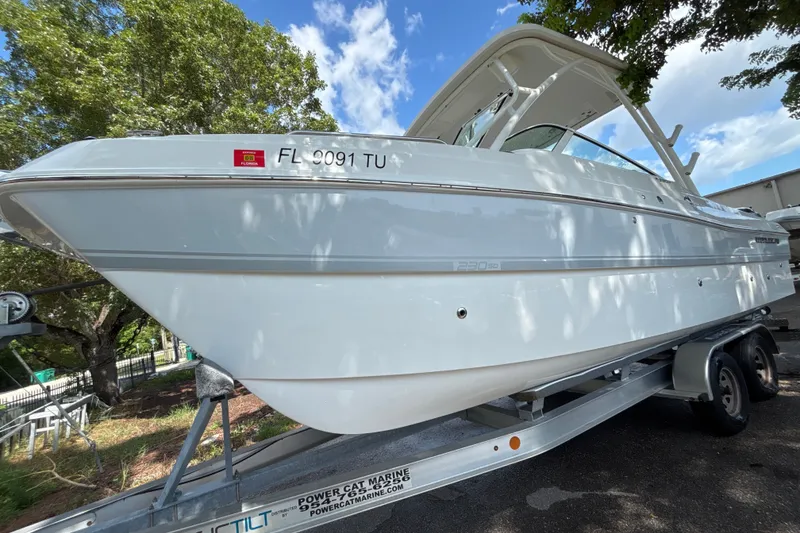 Slide: The Image of 2024 World Cat 230 SD boat on trailer, parked under trees, with Florida registration. - 3