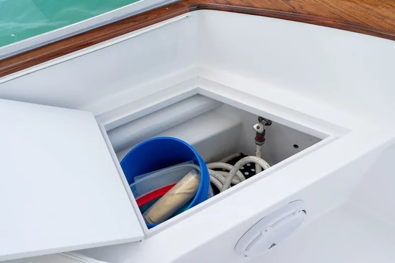 Slide: The Image of Storage compartment on a 2010 Jamie Chadwick 61' Convertible boat with blue bucket and hoses. - 64