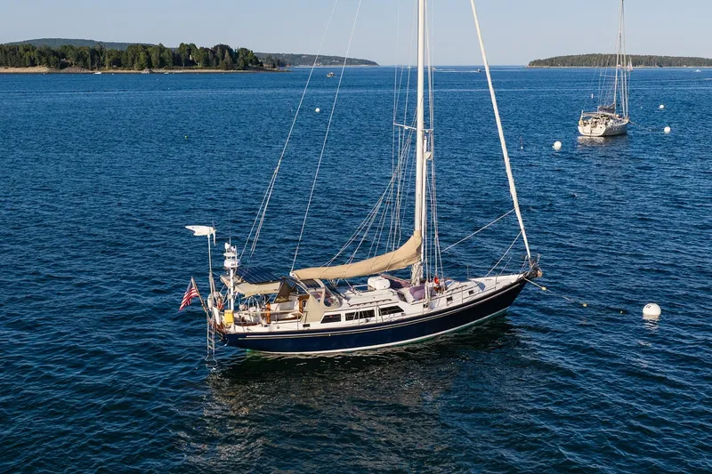 Slide: The Image of Sailboat "Able 42" from 1990 anchored in a serene blue sea with distant islands. - 46