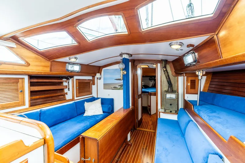 Slide: The Image of Interior of a 1990 Able 42 sailboat with blue seating and wooden finishes. - 26