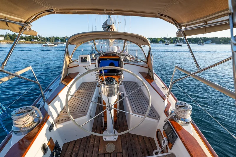 Slide: The Image of Cockpit view of a 1990 Able 42 sailboat on calm waters, featuring a classic wooden steering wheel. - 18