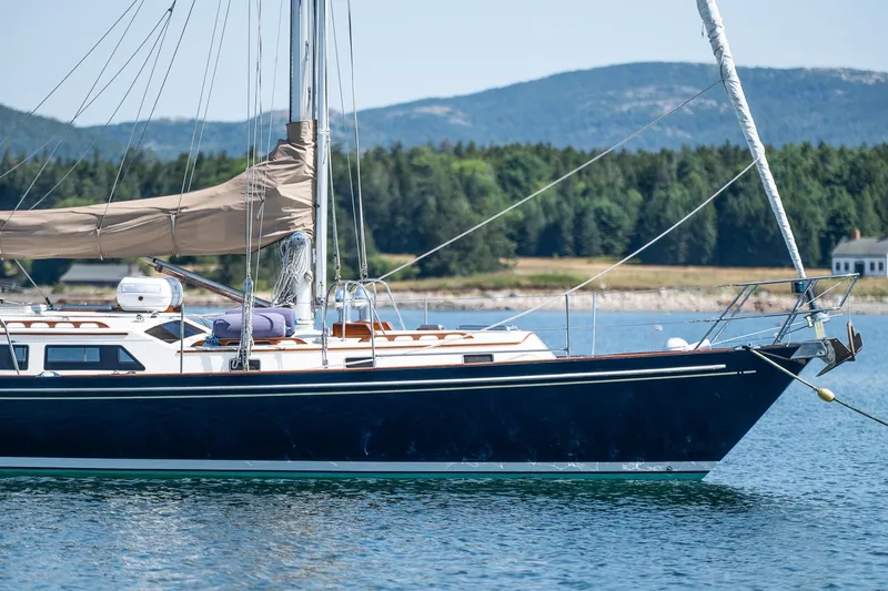 Slide: The Image of Sailboat on calm water, Able 42 model, 1990, with scenic forested hills in the background. - 8