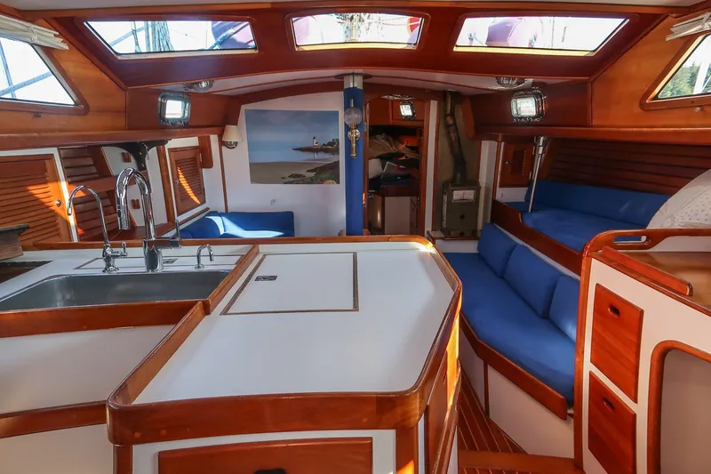 Slide: The Image of Interior of a 1990 Able 42 sailboat with wood finishes and blue seating. - 25