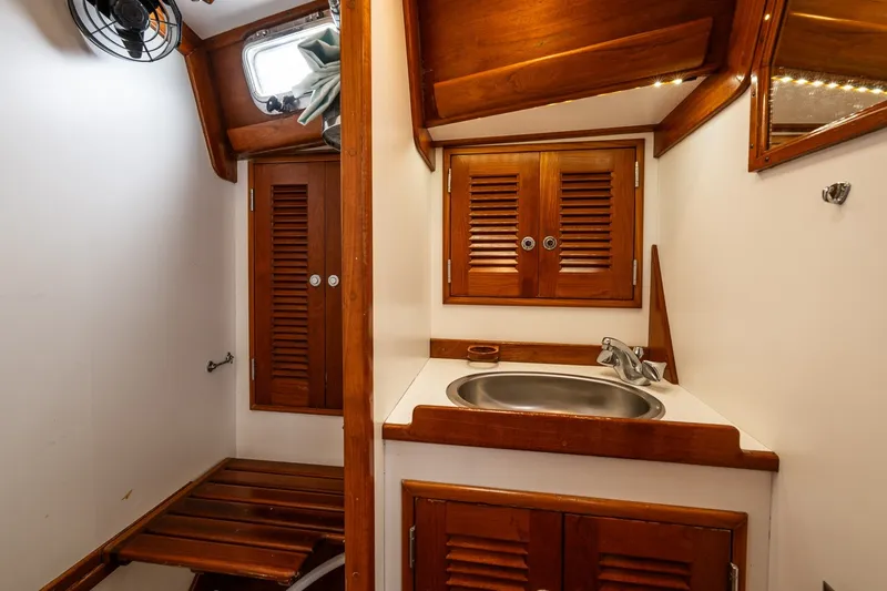 Slide: The Image of Wood-paneled boat bathroom with sink, storage cabinets, and fan, in a 1990 Able 42 model. - 38