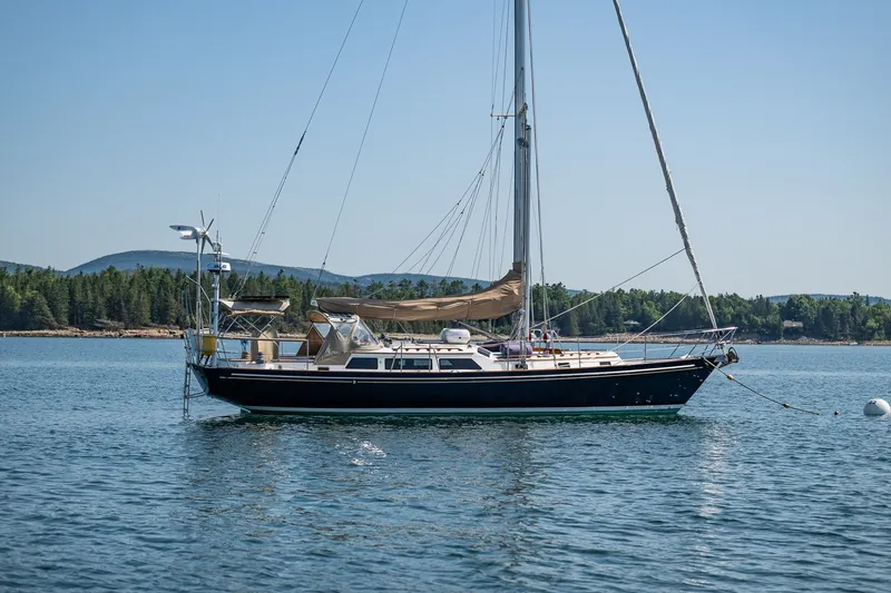 Slide: The Image of Sailboat "Able 42" from 1990 anchored on calm water with forested shoreline. - 4