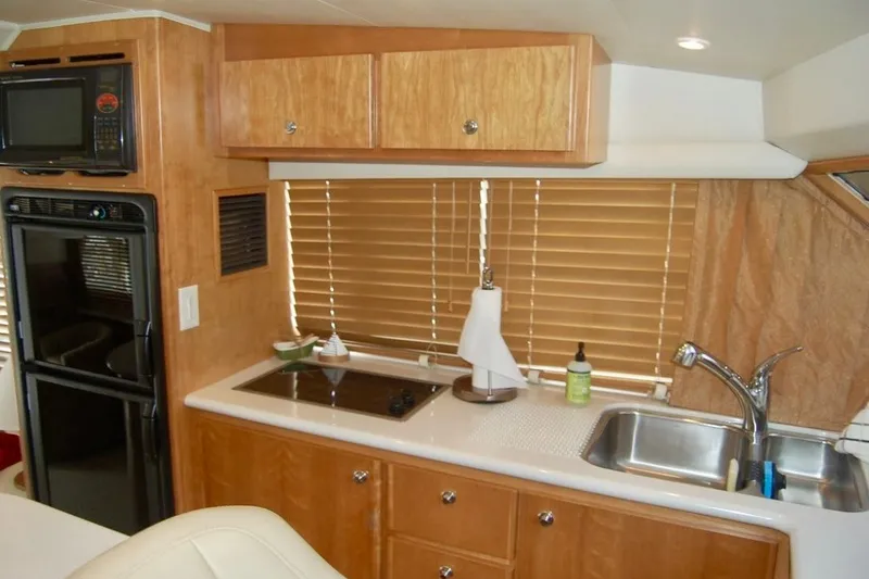 Slide: The Image of 2007 Navigator 44 Classic yacht kitchen with wooden cabinets, stove, sink, and microwave. - 17