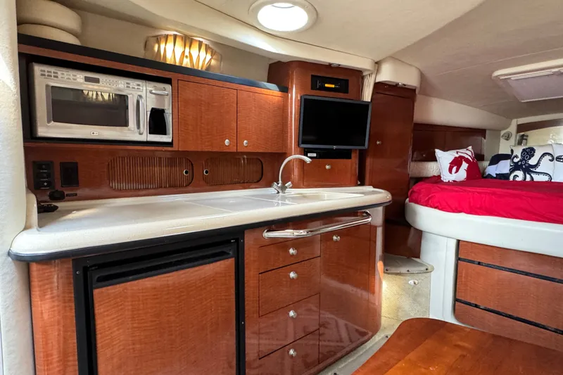 Slide: The Image of 2005 Sea Ray 340 Sundancer interior with kitchenette, microwave, TV, and cozy sleeping area. - 19