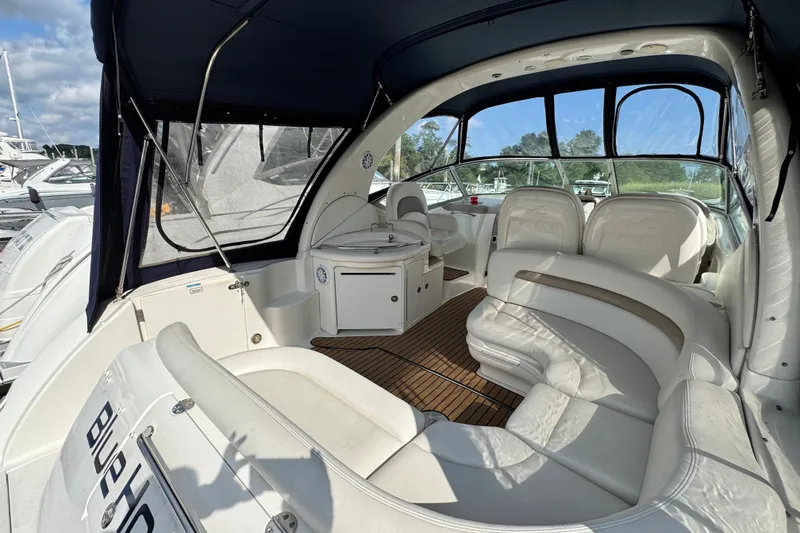Slide: The Image of 2005 Sea Ray 340 Sundancer interior with white seating and wood flooring, docked at marina. - 11