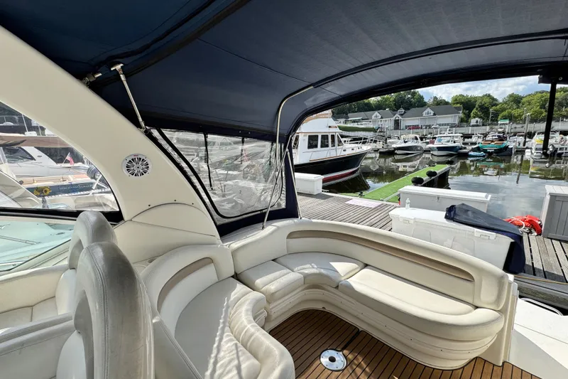 Slide: The Image of 2005 Sea Ray 340 Sundancer interior with marina view, featuring elegant seating and canopy. - 10