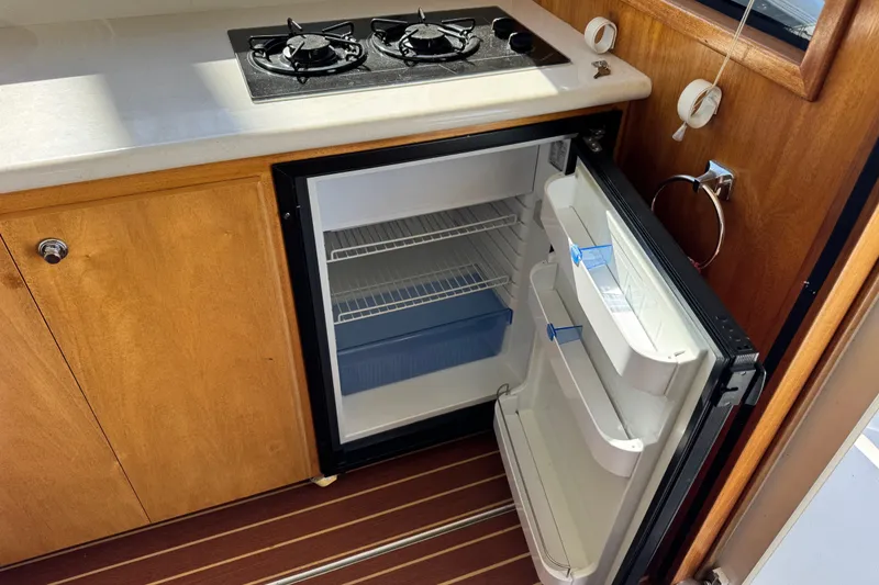 Slide: The Image of Compact kitchen area in 2006 Navigator 34 Californian yacht with open fridge and stove. - 14