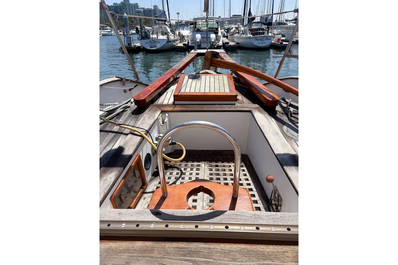 Slide: The Image of 1973 Westsail 32 sailboat cockpit with wooden accents, docked in a marina. - 1