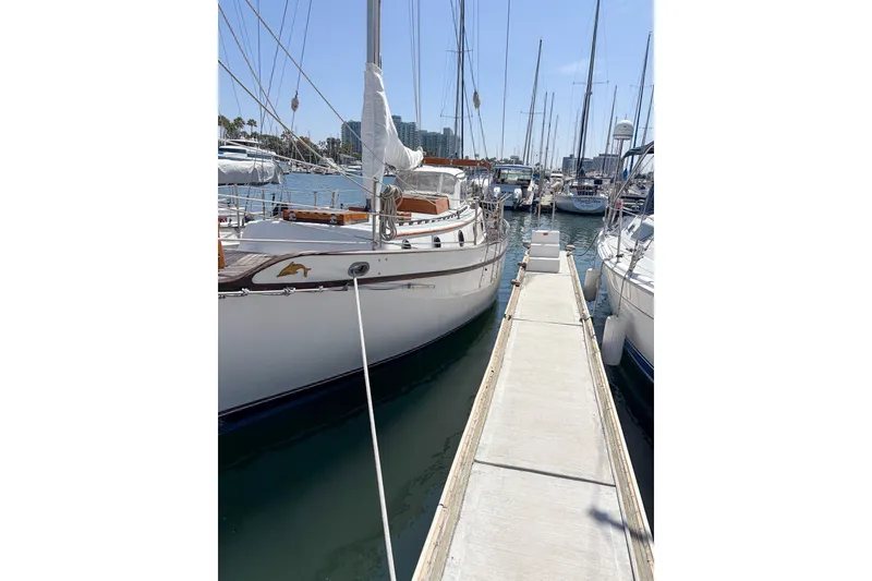 The Image of 1973 Westsail 32 sailboat docked in a marina under clear blue skies. - 0