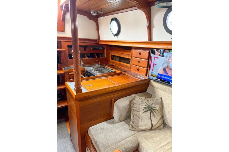 Slide: The Image of 1973 Westsail 32 interior with wooden cabinetry, stove, and cozy seating area. - 10