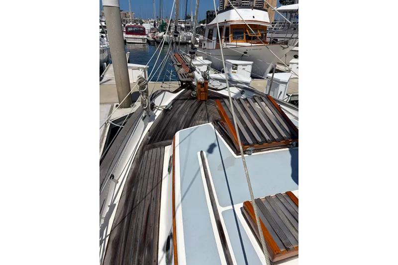 Slide: The Image of 1973 Westsail 32 sailboat deck with wooden accents, docked at a marina. - 3