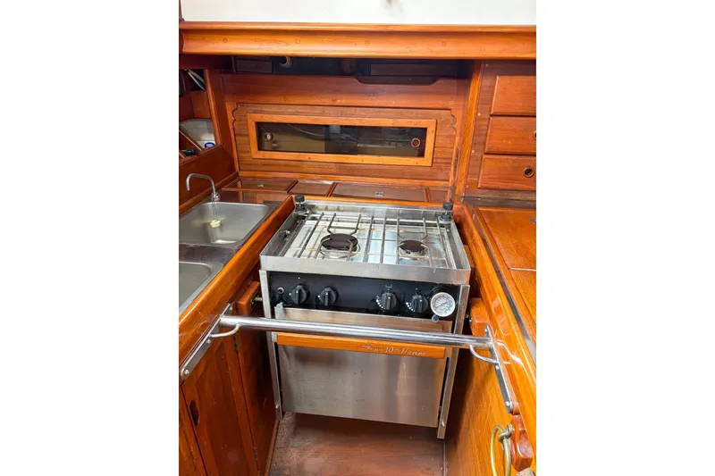 Slide: The Image of 1973 Westsail 32 yacht galley with stove, sink, and wooden cabinetry. - 12