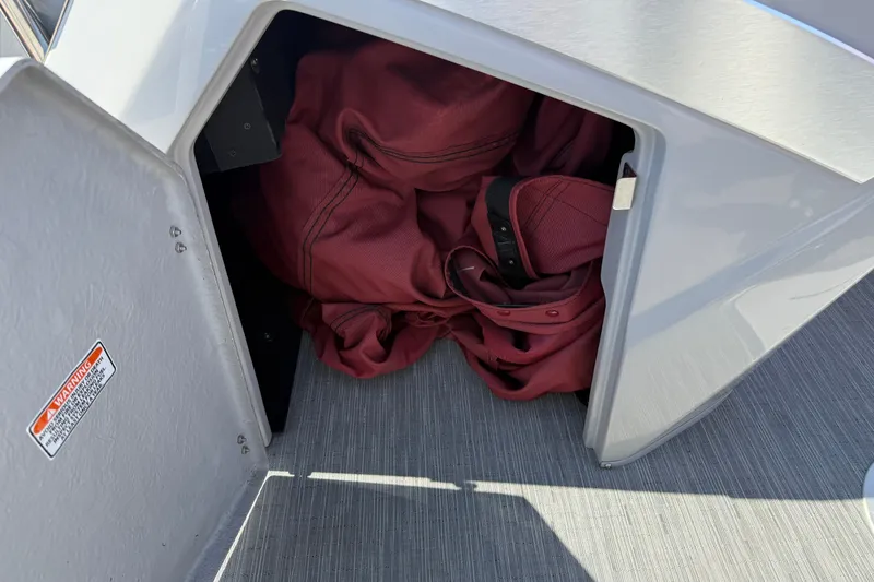 Slide: The Image of Storage compartment on a 2022 Bennington R 24 Quad Bench Bowrider with red fabric inside. - 21