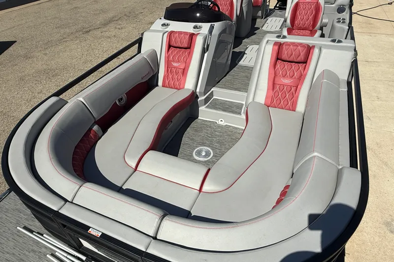 Slide: The Image of 2022 Bennington R 24 Quad Bench Bowrider with red and gray seating, docked on a sunny day. - 9