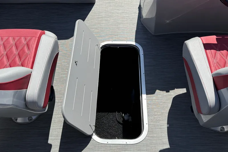 Slide: The Image of 2022 Bennington R 24 Quad Bench Bowrider with open storage compartment between red seats. - 20