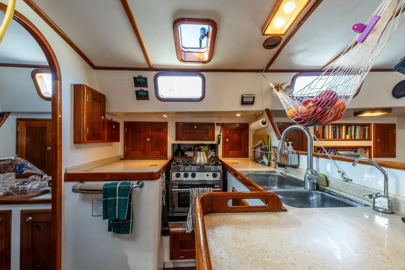 Slide: The Image of Cozy kitchen interior of 1993 Van De Stadt Samoa 47 yacht with wooden cabinets and fruit hammock. - 15
