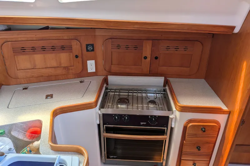 Slide: The Image of Compact kitchen area in a 2005 C&C 115 sailboat with stove and wooden cabinetry. - 40