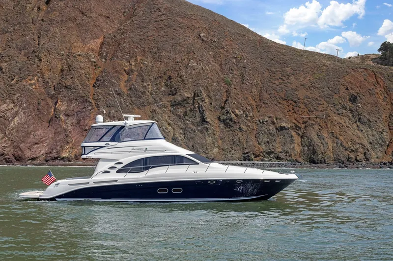 Slide: The Image of 2007 Sea Ray 58 Sedan Bridge yacht cruising near rocky coastline under blue sky. - 3