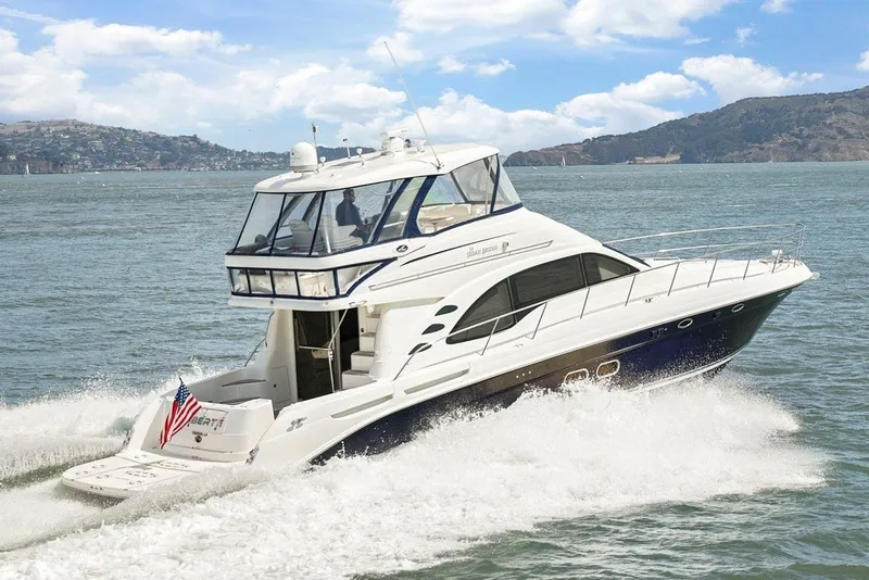 The Image of The 2007 Sea Ray 58 Sedan Bridge cruises on calm waters with a scenic mountain backdrop. - 0