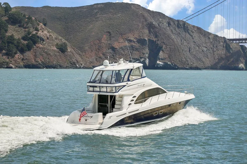 Slide: The Image of 2007 Sea Ray 58 Sedan Bridge yacht cruising near rocky coastline and bridge. - 12