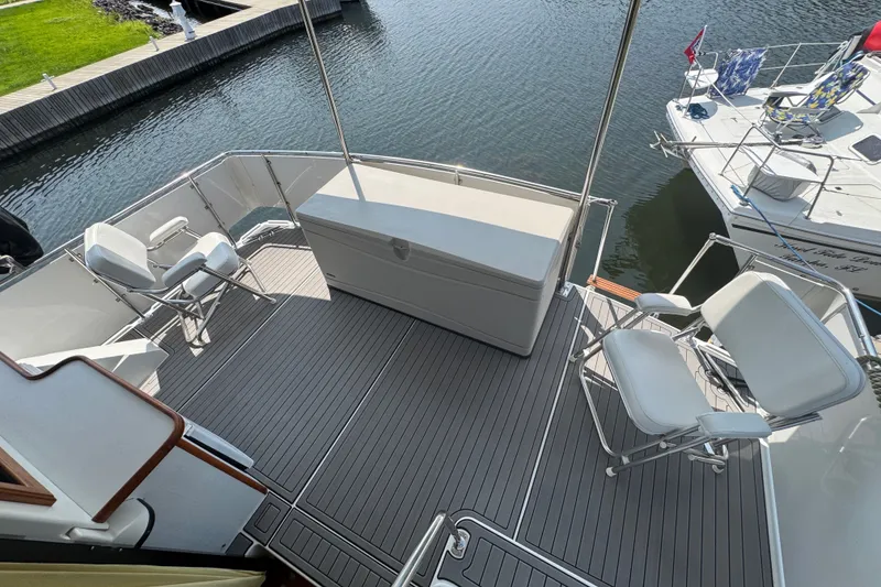 Slide: The Image of 1990 Carver 3807 Aft Cabin Motor Yacht deck with seating and storage, docked by water. - 33