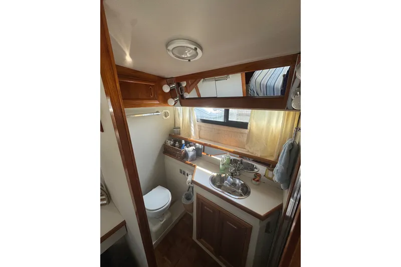 Slide: The Image of 1990 Carver 3807 Aft Cabin Motor Yacht bathroom with sink, toilet, and wooden cabinetry. - 27