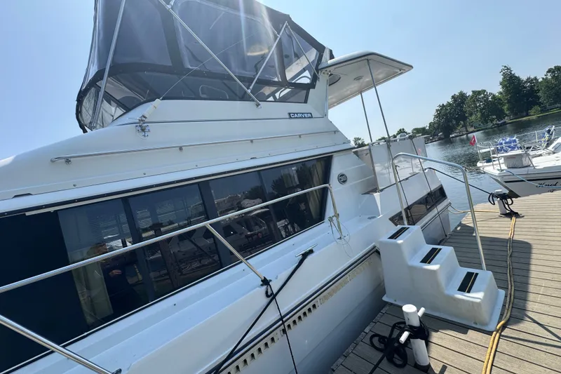 Slide: The Image of 1990 Carver 3807 Aft Cabin Motor Yacht docked by a serene waterfront. - 5