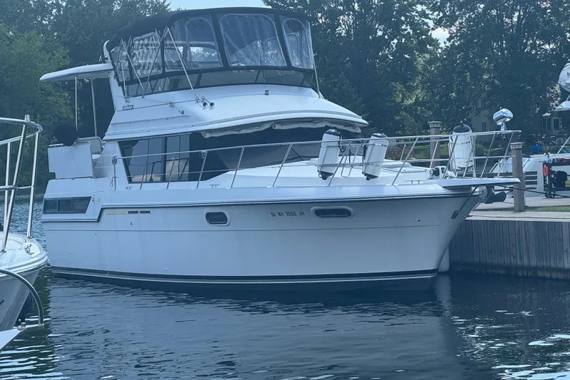 Slide: The Image of 1990 Carver 3807 Aft Cabin Motor Yacht docked by a serene waterfront. - 3