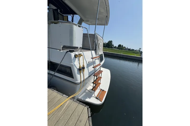 Slide: The Image of 1990 Carver 3807 Aft Cabin Motor Yacht docked, featuring wooden steps and water reflection. - 8