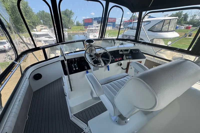 Slide: The Image of 1990 Carver 3807 Aft Cabin Motor Yacht helm with steering wheel and controls. - 49