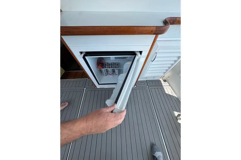 Slide: The Image of Hand opening mini fridge on 1990 Carver 3807 Aft Cabin Motor Yacht deck. - 31